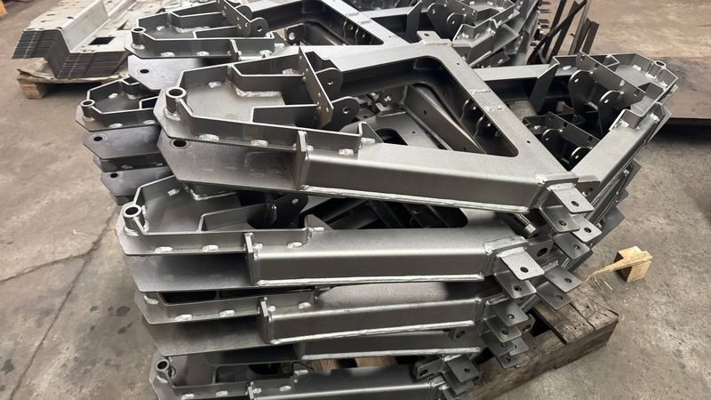 Primed welded steel brackets stacked on a pallet